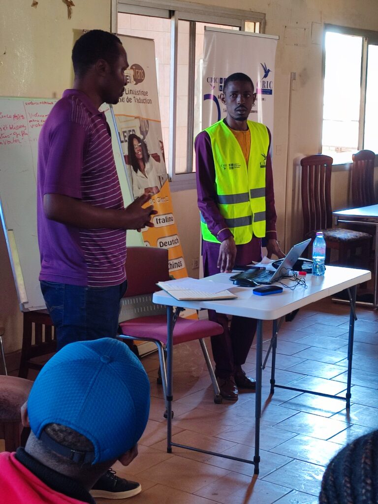 Deux animateurs, dont l’un en gilet jaune, présentent l’École itinérante de prévention des VBG à des jeunes